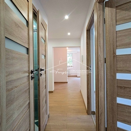 Przestronny salon z aneksem kuchennym tworzy serce tego przytulnego mieszkania.