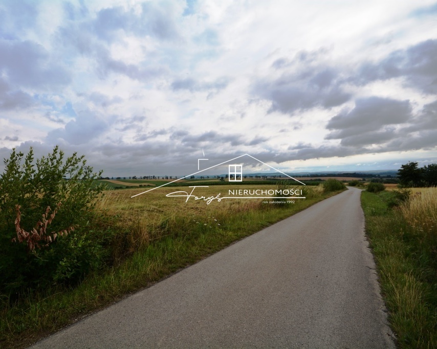 Płaska, prostokątna działka w otoczeniu zieleni i zabudowy jednorodzinnej.